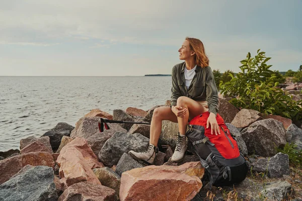 Plezierige reiziger rustend op rotsen met haar rugzak — Stockfoto