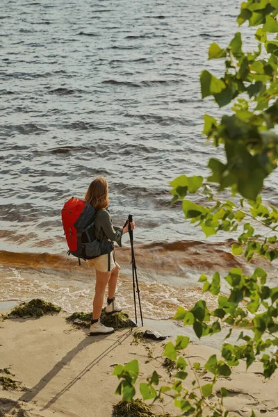 Toerist staat op een strand met wandelpalen — Stockfoto