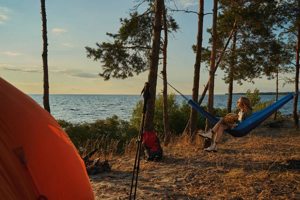 Resenär tittar på solnedgången från hängmatta med blombukett — Stockfoto