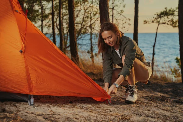 Vivace donna che installa una tenda arancione nel bosco — Foto Stock
