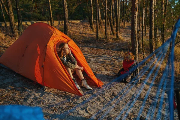 Kvinna vilar i tält medan du tittar på solnedgången — Stockfoto