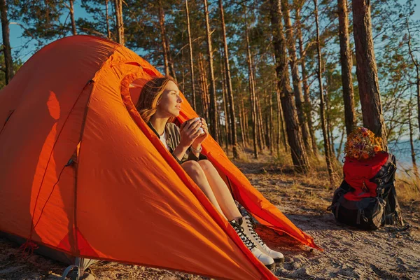 Vandrare smuttar te på solnedgången i hennes tält — Stockfoto