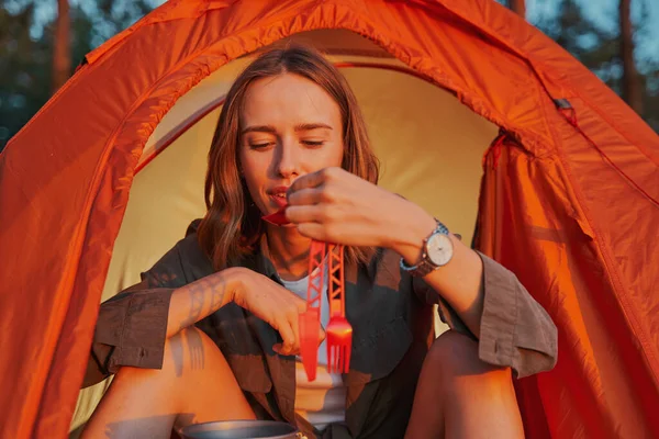 Femmina in tenda portando cucchiaino alla bocca — Foto Stock