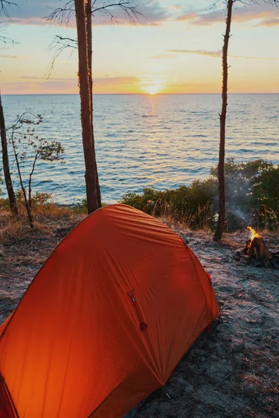 Tenda accanto a un falò in fiamme sulla riva del lago — Foto Stock