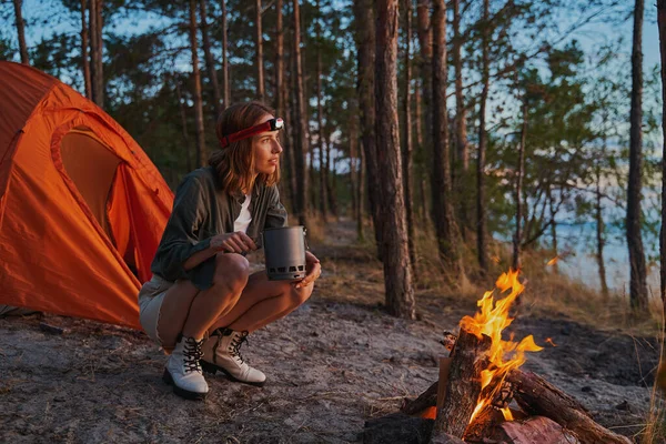 Viaggiatori seduti accanto al fuoco ardente nel bosco — Foto Stock