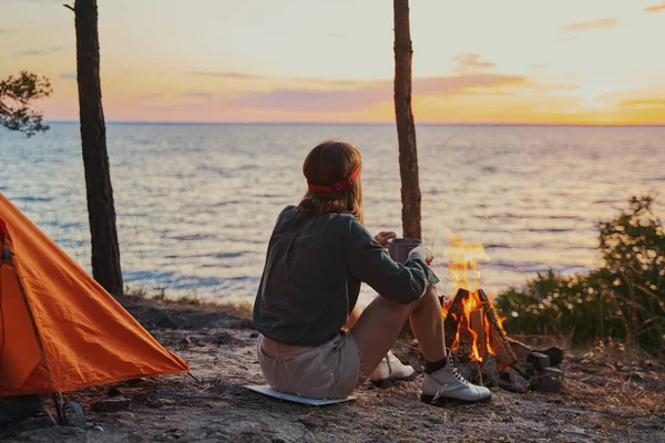 Backpacker che osserva la superficie dell'acqua mentre riposa al fuoco di legna — Foto Stock