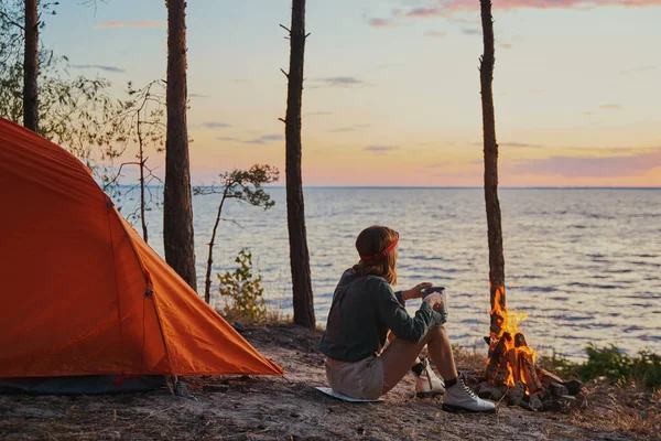 Persona incontro tramonto al lago vicino al fuoco del campeggio — Foto Stock