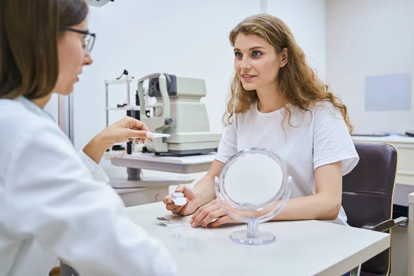 Beautiful young woman having consultation with oculist in clinic — Stock Photo, Image