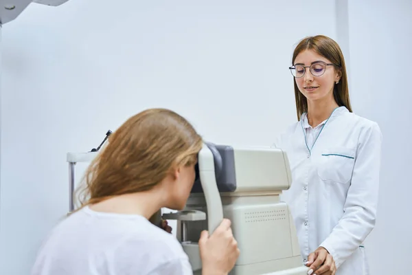 Kvinnlig optiker kontrollerar kvinnliga ögon med autorefraktor — Stockfoto