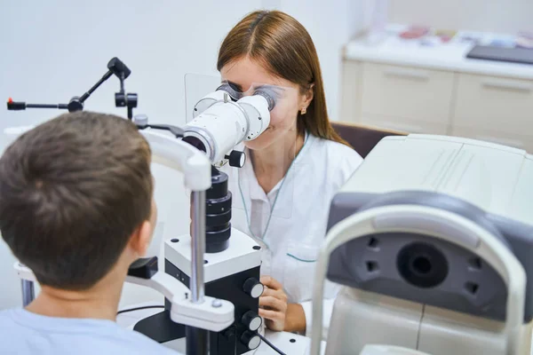 Доктор вивчає дитячі очі з офтальмологічним обладнанням — стокове фото