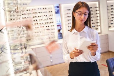 Optik mağazada dijital tablet bilgisayar kullanan güzel bir kadın