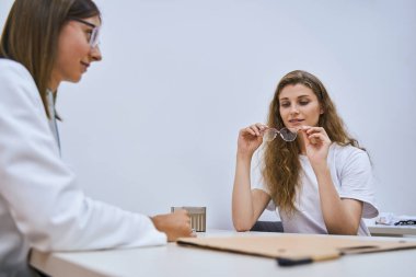 Göz doktoruyla klinikte randevusu olan çekici genç bir kadın.