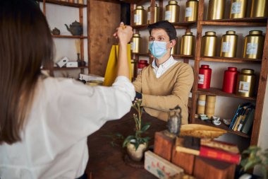 Esmer genç bir kadın çay dükkanından alışveriş yapıyor.
