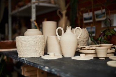 Atölyede el yapımı çömlek bulunan ahşap masa.