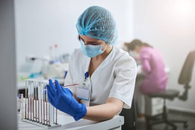 Tıbbi laboratuvar bilim adamı klinik bir örneği inceliyor.