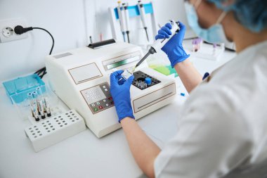 Tıbbi laboratuvar teknisyeni bir ilaç şişesinden sıvı çekiyor.