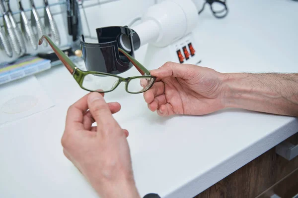 Mãos óticas masculinas segurando óculos com moldura verde — Fotografia de Stock