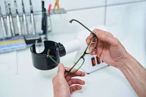 Mãos óticas masculinas segurando óculos com moldura verde — Fotografia de Stock