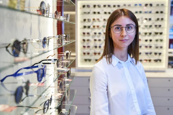 Schöne junge Frau mit Brille steht im Optikgeschäft — Stockfoto