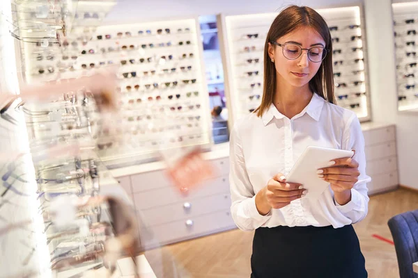 Mujer hermosa usando tableta digital en la tienda óptica — Foto de Stock