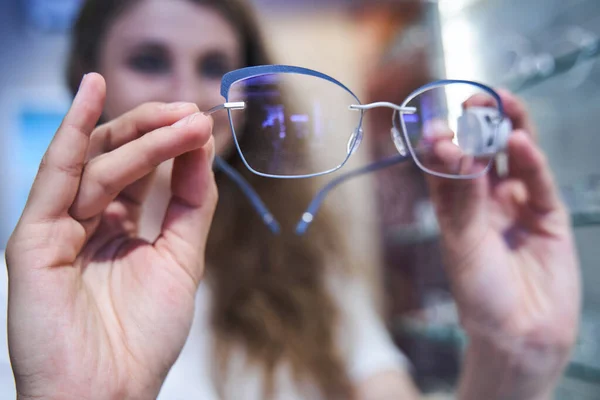 Jovem mulher escolhendo óculos na loja óptica — Fotografia de Stock