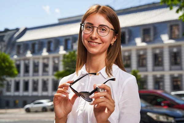 Радісна молода жінка в окулярах стоїть на вулиці — стокове фото