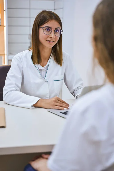 Encantadora doctora teniendo cita con paciente en clínica —  Fotos de Stock
