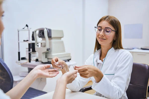 Glada optiker som ger glasögon till kvinnan på kliniken — Stockfoto