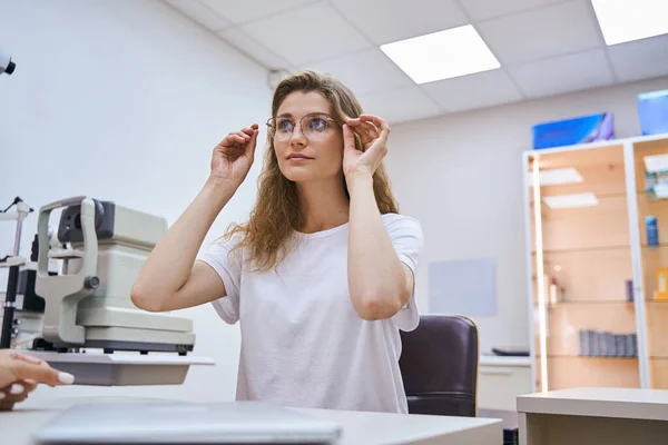Charmante junge Frau probiert Brille im Optikerbüro an — Stockfoto