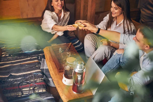 Amigos alegres brindando con tazas de té en la cafetería — Foto de Stock