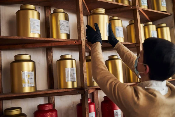 Mannelijke arbeider neemt gouden kruik thee van de plank — Stockfoto