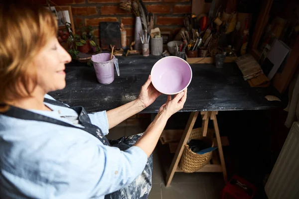 Жінка-художниця тримає розфарбовану чашу в керамічній майстерні — стокове фото