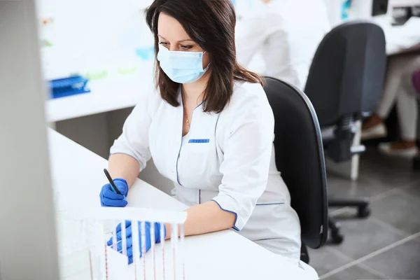 Ernstige biochemicus met een pen in één hand verloren in gedachten — Stockfoto