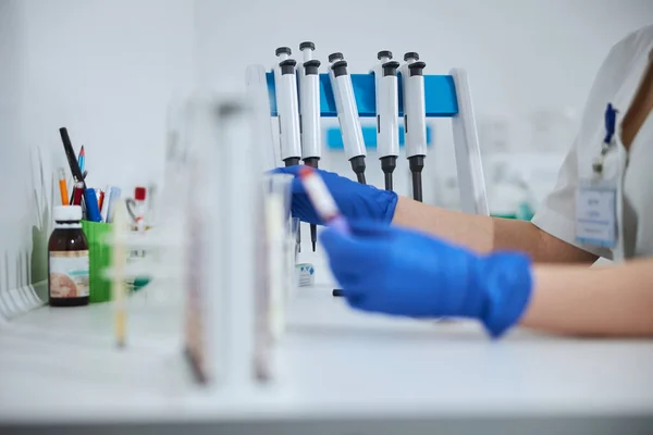 Woman in a lab coat holding a vacutainer with both hands — Stock Photo, Image