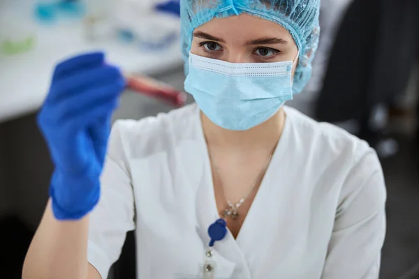 Lékařský laboratorní vědec drží zkumavku před očima — Stock fotografie