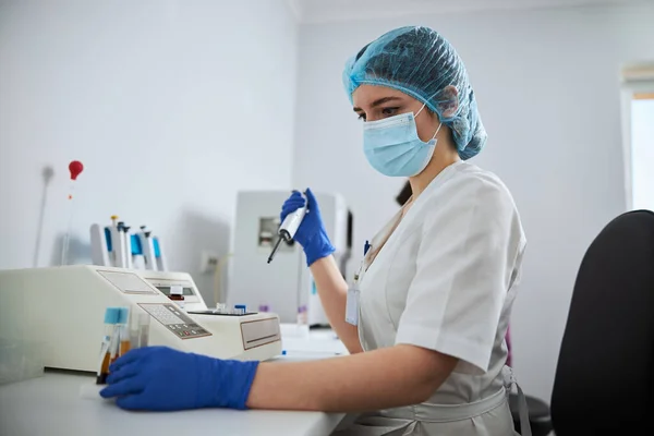 Focused lab technician preparing clinical specimens for a coagulation analysis — Stock Photo, Image