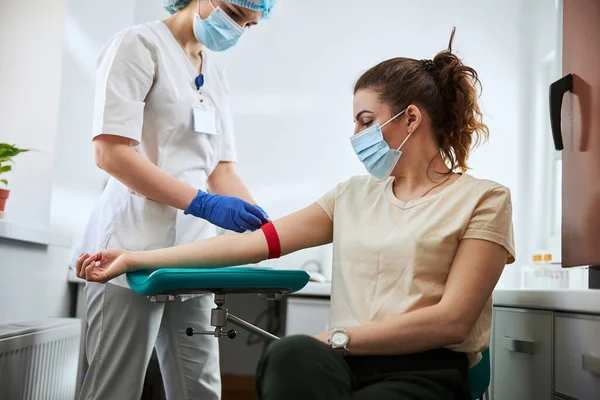 Flebotomista experimentado preparando a una mujer para la extracción de sangre — Foto de Stock