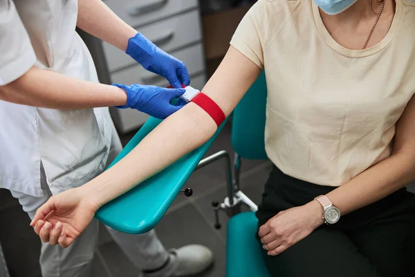 Phlebotomy tekniker dra åt det elastiska bandet på patientens arm — Stockfoto