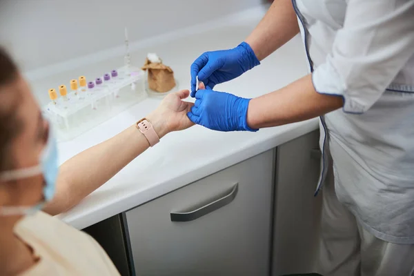 Enfermera preparando a una hembra para un análisis de sangre con pinchazo en el dedo — Foto de Stock