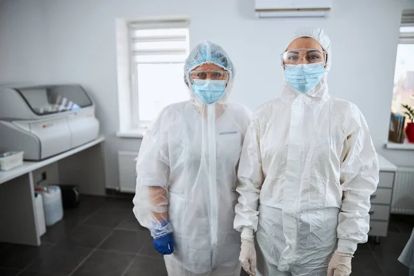 Two serious scientists in hazmat suits standing in the research lab — Stock Photo, Image