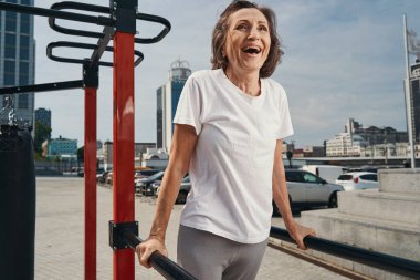 Neşeli olgun sporcu kadın açık havada egzersiz yapıyor.