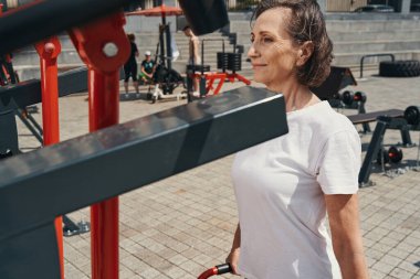 Gülümseyen aktif kadın açık havada egzersiz yapıyor.