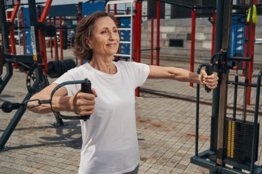 Mutlu yaşlı kadın kablolarla antrenman yapıyor.