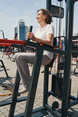 Neşeli olgun kadın dışarıda karın kasılmaları yapıyor.