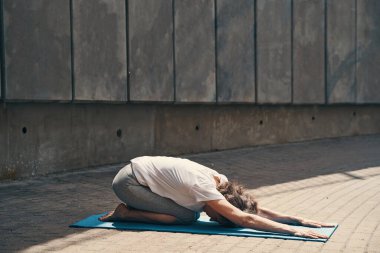 Son sınıf öğrencisi sıska bir kadın, güneşte esneme egzersizleri yapıyor.