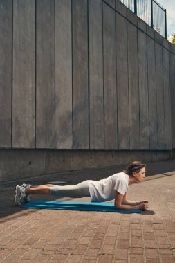 Dışarıda vücut kaslarını çalıştıran neşeli, formda bir bayan.