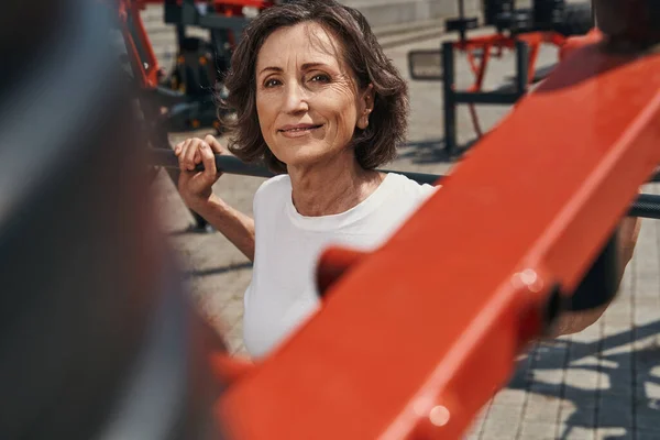 Smiling mature woman working out on sports ground — Foto de Stock
