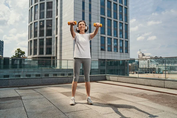 Feliz senhora ativa fazendo exercício no telhado urbano — Fotografia de Stock