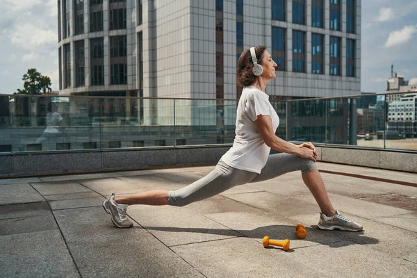 Sereno maduro feminino fazendo fitness no centro da cidade — Fotografia de Stock