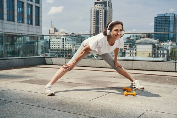 Sorrindo mulher muito idosa se exercitando no telhado urbano — Fotografia de Stock